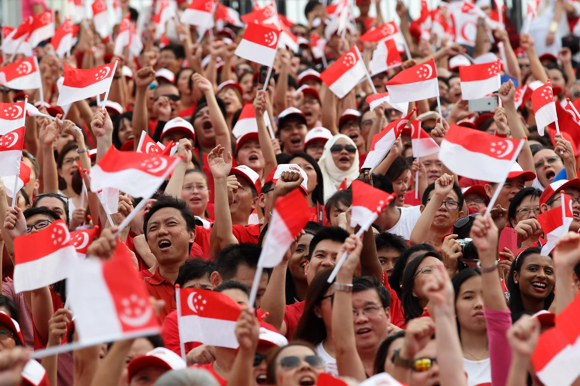 SINGAPORE - AUGUST 09:  People wave the flags during the National Day Parade at Padang on August 9, 2015 in Singapore. Singapore is celebrating her 50th year of independence on August 9, 2015.  (Photo by Suhaimi Abdullah/Getty Images)