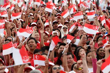 SINGAPORE - AUGUST 09:  People wave the flags during the National Day Parade at Padang on August 9, 2015 in Singapore. Singapore is celebrating her 50th year of independence on August 9, 2015.  (Photo by Suhaimi Abdullah/Getty Images)