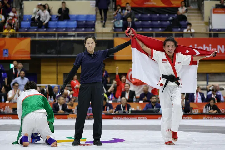 Tiffany Teo of Singapore being announced the winner, as Khilola Sobirova of Uzbekistan drops to her knees, during the mixed martial arts women's traditional (60kg) final of the Aichi-Nagoya 2026 Asian Games at the Nagoya City Inae Sports Centre in Nagoya, Japan on Sept 22, 2026. ST PHOTO: KEVIN LIM pixag22