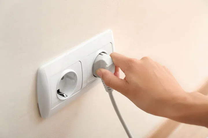 Woman getting out plug from socket.  Electricity saving concept