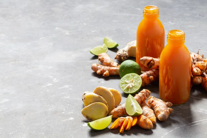 Healthy drink from turmeric and ginger roots and lime in small bottles on grey concrete background with copyspace. Jamu - popular Indonesian traditional drink on Bali. Immunity boosting, detox, diet.