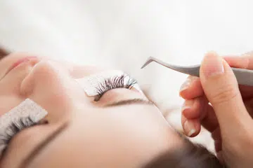 woman getting false eyelashes and a home-based eyebrow and lash salon