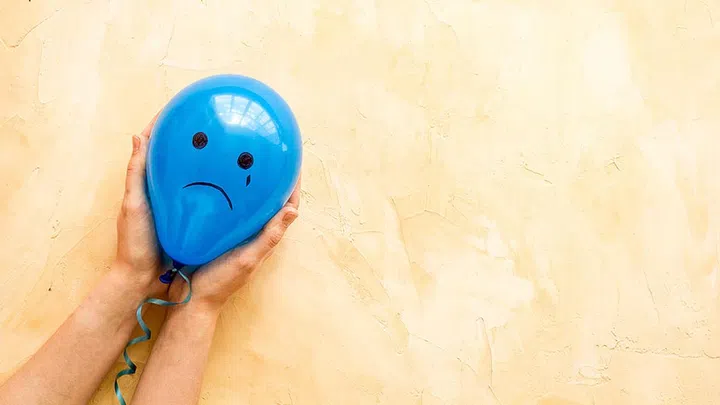 Sadness emotion face on balloon - mood background. Top view, copy space.