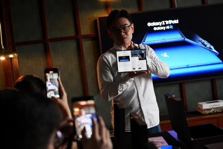 Mr Eric Wong, product trainer (mobile experience) from Samsung Electronics Singapore, presenting the Samsung Galaxy Z TriFold on Dec 3, 2025. The phone, which is about 7cm wide, can be unfolded into a 21.4cm screen featuring three panels that blend seamlessly into a single tablet-size screen.
