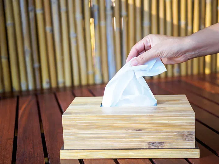 Woman hand picking a white tissue from tissue box.