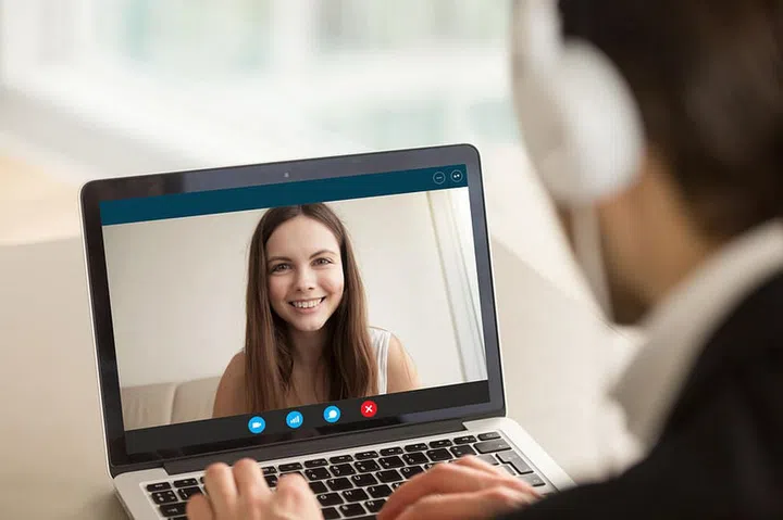 Smiling girl on videocall with guy, making video call to close foreign friend, talking by web camera, using virtual chat app online, long distance relationships, focus on screen, close up rear view