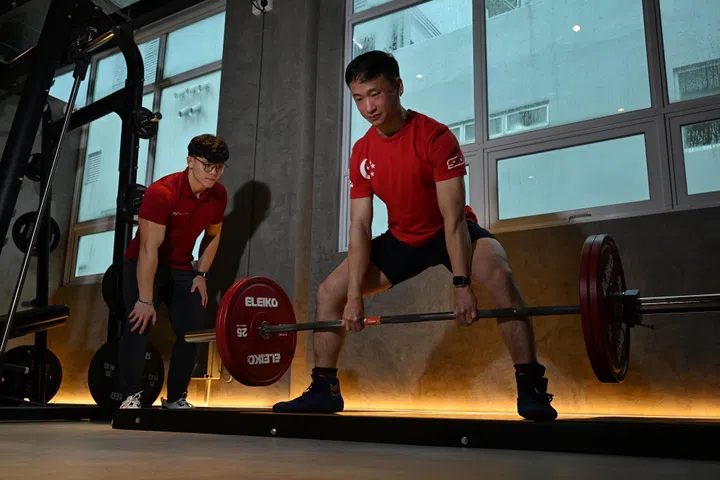 Kester Lim (left), manager of ReFormd Personal Training and competitive powerlifter Ong Wei Chaai during a training session, 20 March 2025.