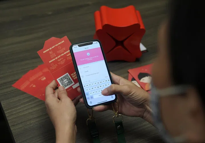 lwhongbao19 / ST20210115_202117841427 / Alphonsus Chern //

A customer demonstrating the use of the e-hongbao with a QR code.

A DBS customer uses the e-hongbao functions on her phone. Please note that there are two functions from DBS: the first is QR Gift, which involves a hongbao with a QR code instead of cash which recipients scan to receive money. The second is a fully digital option called DBS eGift, which is like CNY PayNow - users transfer money to their relatives and can send CNY messages, greetings or animations.