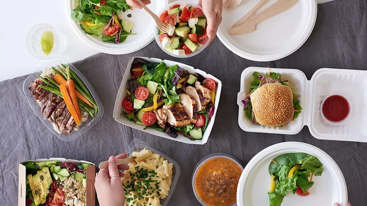 Convenient takeaway takeout food for party, overhead spread of assorted food with hands serving up