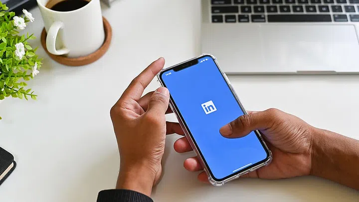 CHIANGMAI, THAILAND - MARCH 30, 2019: A man holds Apple iPhone XS Max open LinkedIn application on the screen. An LinkedIn is a business oriented social networking service.
