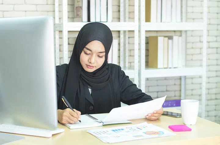 Young beautiful asian muslim business woman wearing black hijab,working at coworking place.