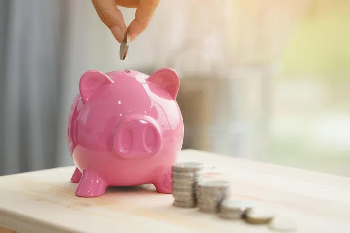 Little hand saving money in pink piggy bank