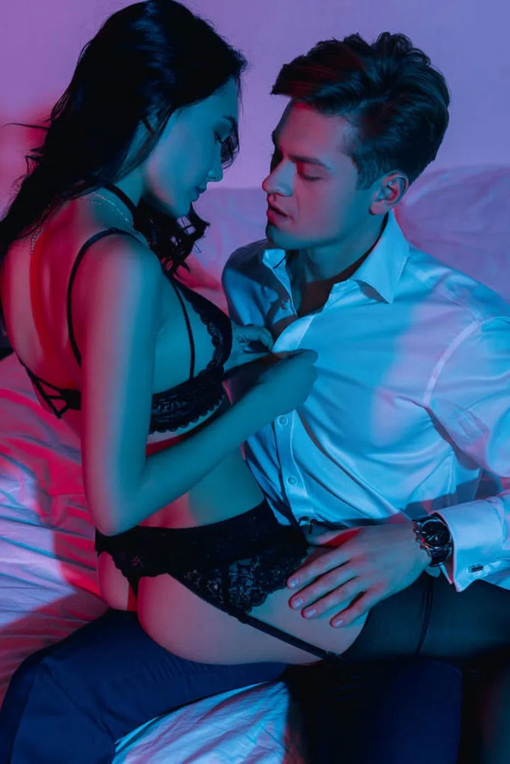passionate woman in lingerie undressing her boyfriend in bed