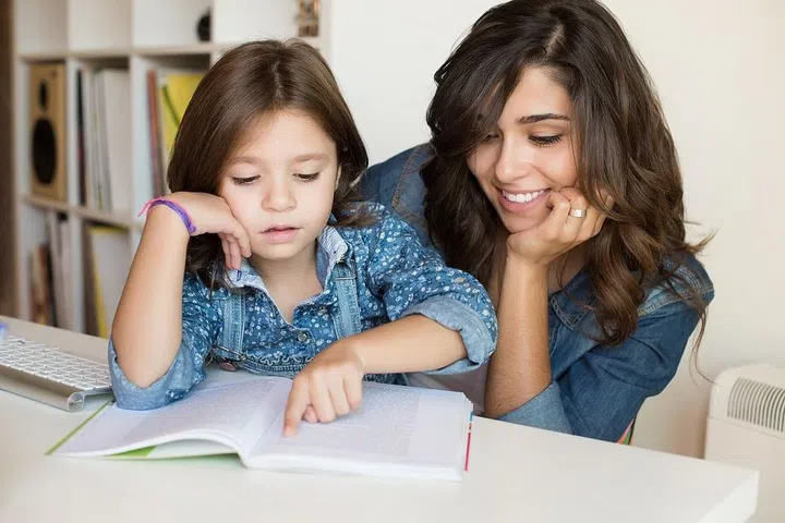 Mother helping her little child with homework