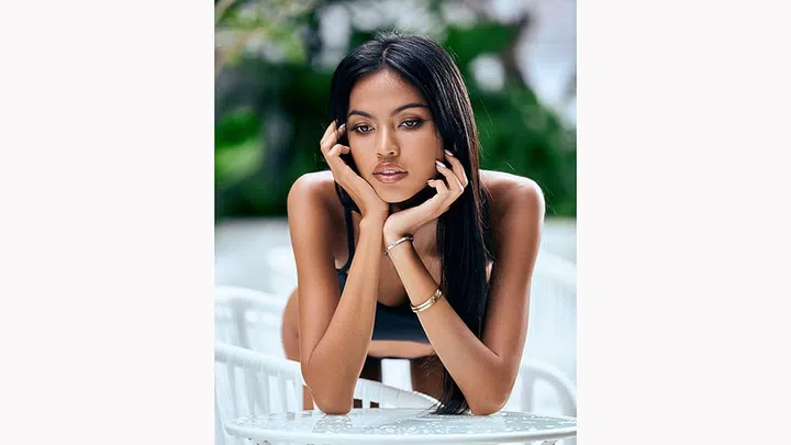 Close-Up portrait of young asian sexy woman in a black bikini posing on white chair at hotel territory