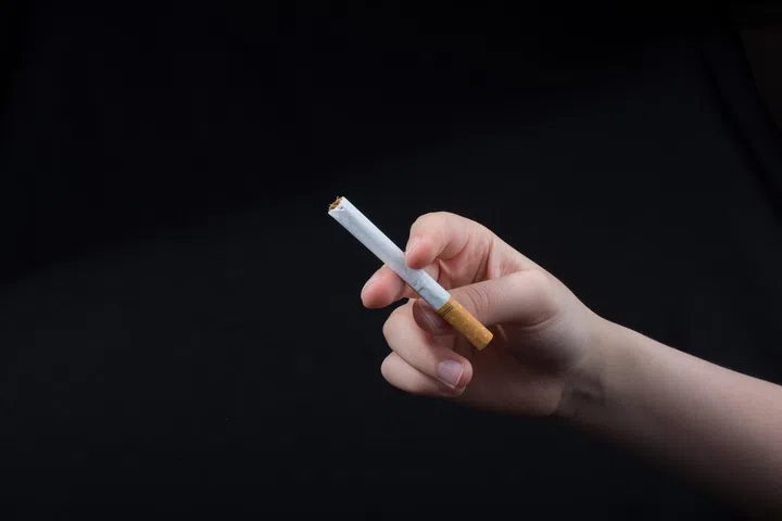 Hand is holding a cigarette on black background