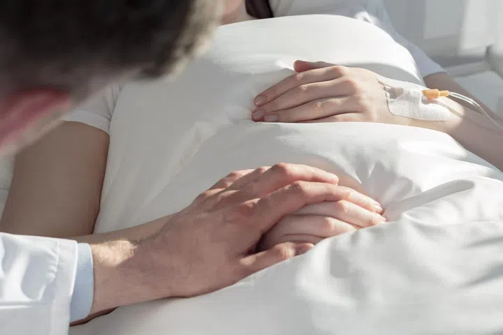 Close up of oncologist holding hand of girl with leukemia