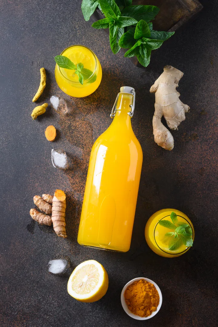 Jamu Indonesian herbal beverage in bottle with natural ingredients turmeric, ginger on brown background. Vertical. View from above.
