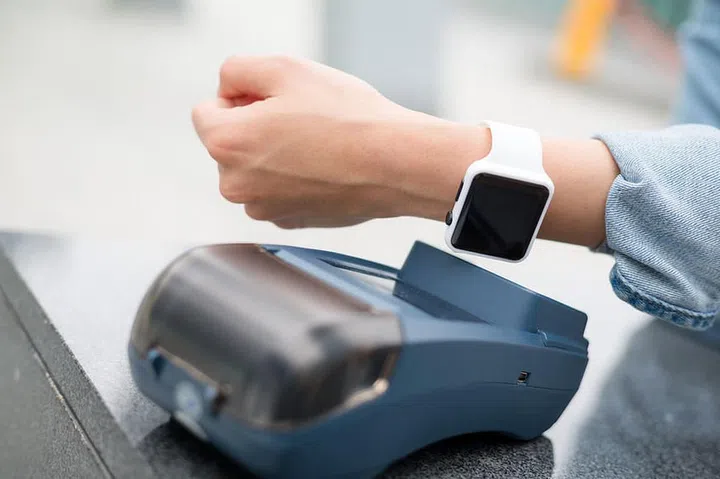 Woman paying the bill by smart watch by NFC technology
