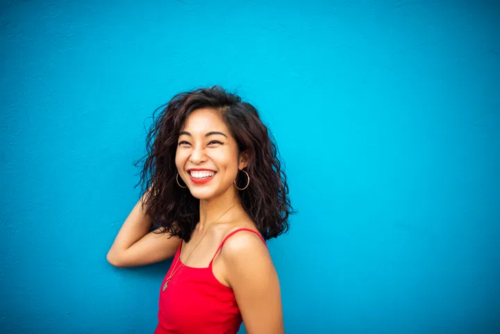 Portrait of a smiling Asian woman on a blue wall