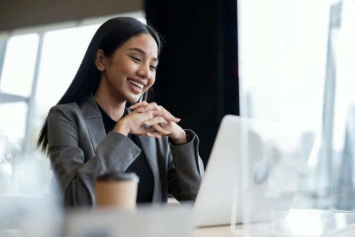 Video Cloud Conferences Improve Business Connecting. Young woman having video call on her laptop with client or business team to discuss on a business project in a modern business office.