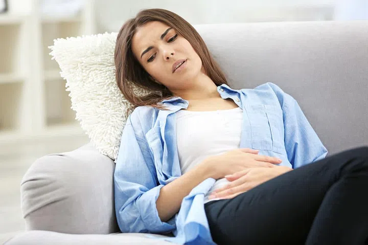 Young woman suffering from abdominal pain at home. Gynecology concept