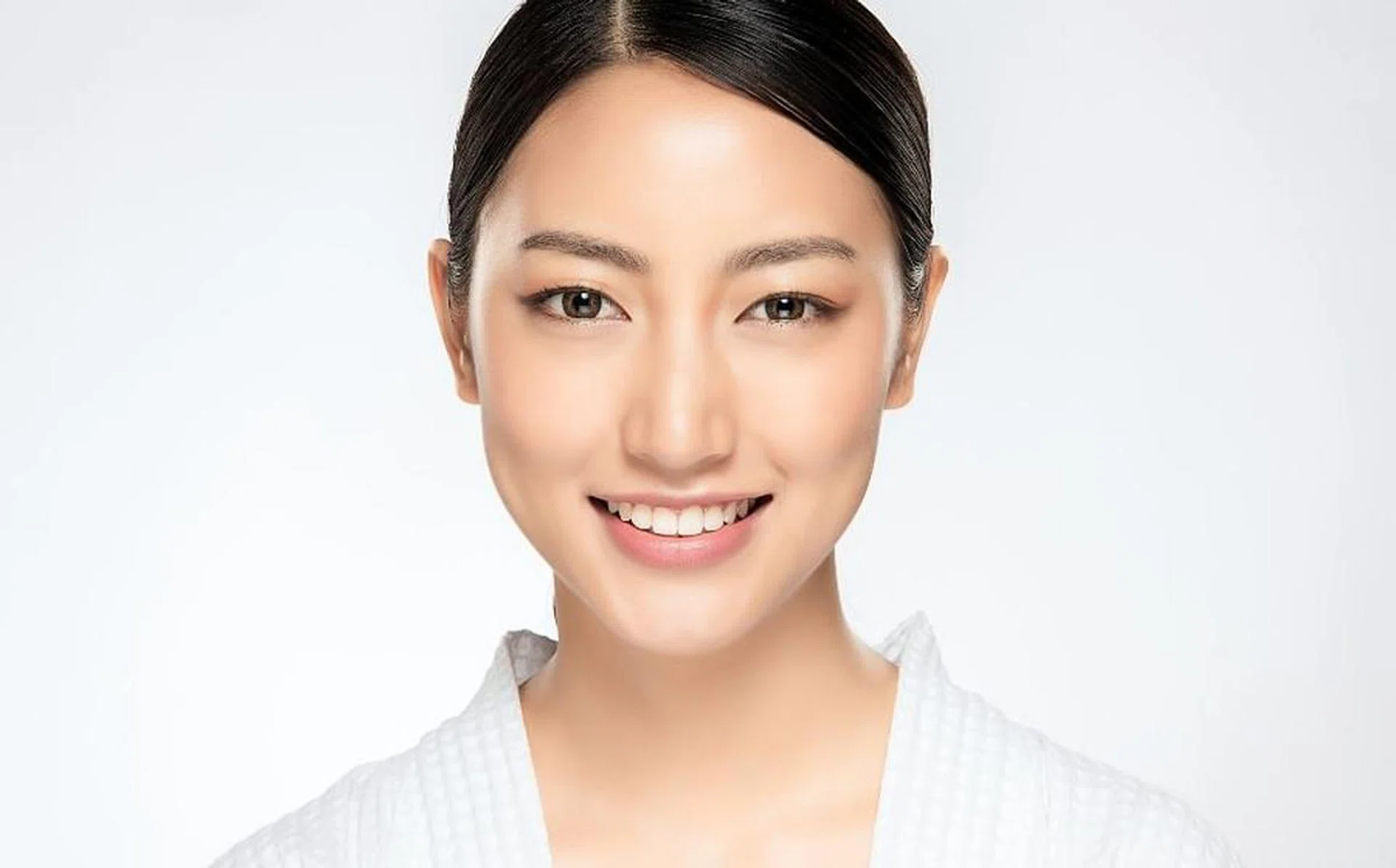 Beautiful smiling woman with clean skin, natural make-up, and white teeth on white background