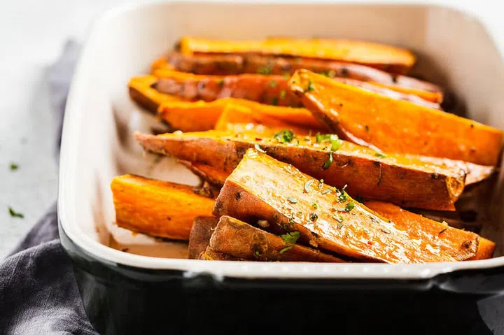 Baked sweet potato slices with spices in the oven dish. Healthy vegan food concept.