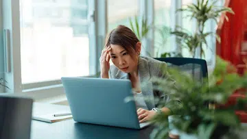 Tired Asian businesswoman working on a laptop computer in the office | Year of the fire horse, 2026 career forecast