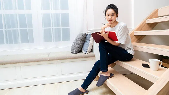 Young hipster woman writing journal on small notebook