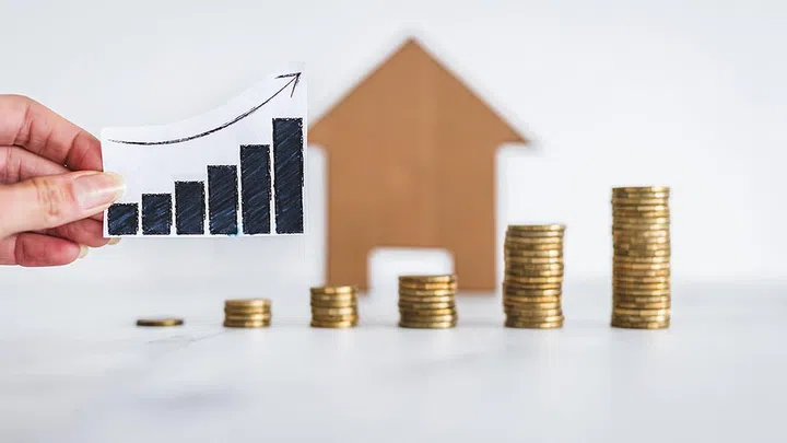 interest rates for loans and real estate prices going up conceptual image, graph with upward trend with growing stacks of coins in front of cardboard house