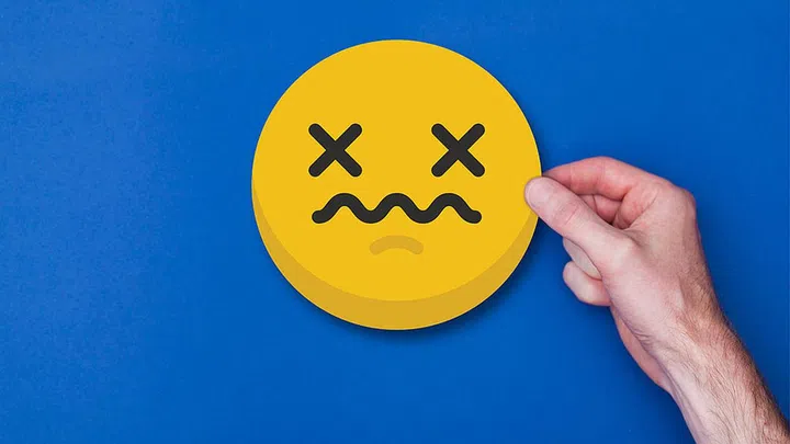 Male hand holding a emoji emoticon unhappy smiley head icon