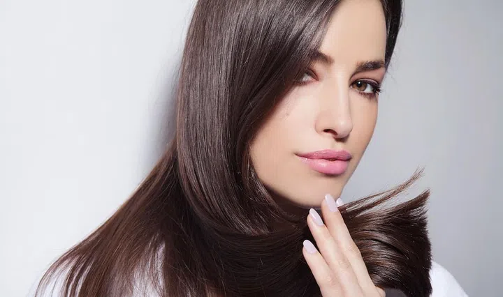 beautiful young woman holding her healthy and shiny hair, studio white