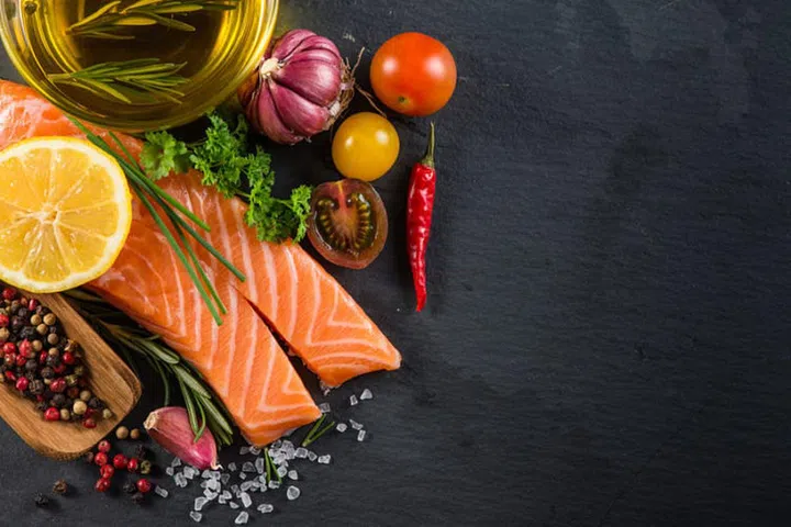 37028217 - portion of fresh salmon with spices,herbs and vegetables on black slate background