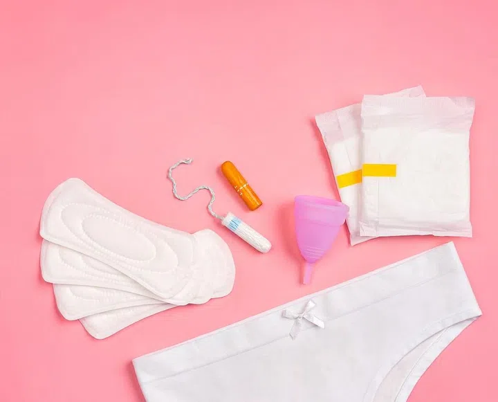 White pants with sanitary napkins, tampons, menstrual cup on pink background. Concept of critical days, menstruation