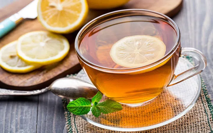 Cup of tea with mint and lemon on wooden table