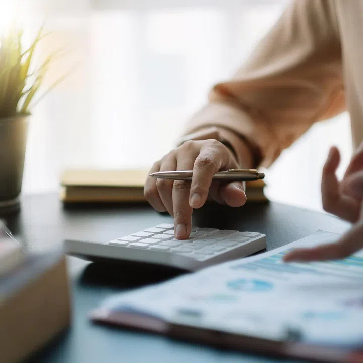 businessman working on desk office with using a calculator to calculate the numbers, finance accounting concept