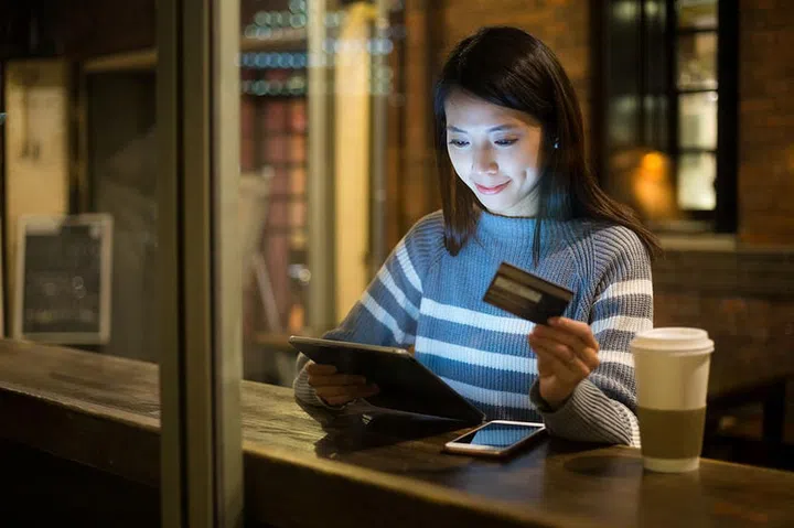 Young woman using credit card for paying on tablet
