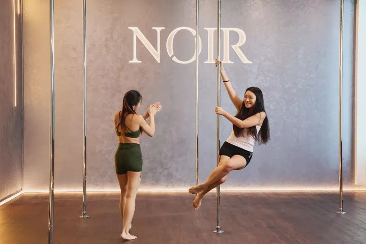 The Geisha / Pole Sit: Lift your left leg to sit over your right, which is hooked in front of the pole, while your arms support your weight higher up.
