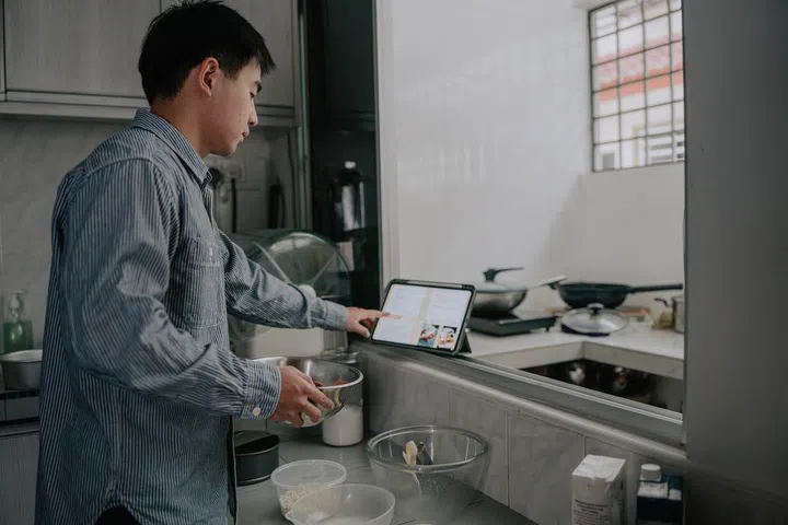 Asian man using tablet while cooking