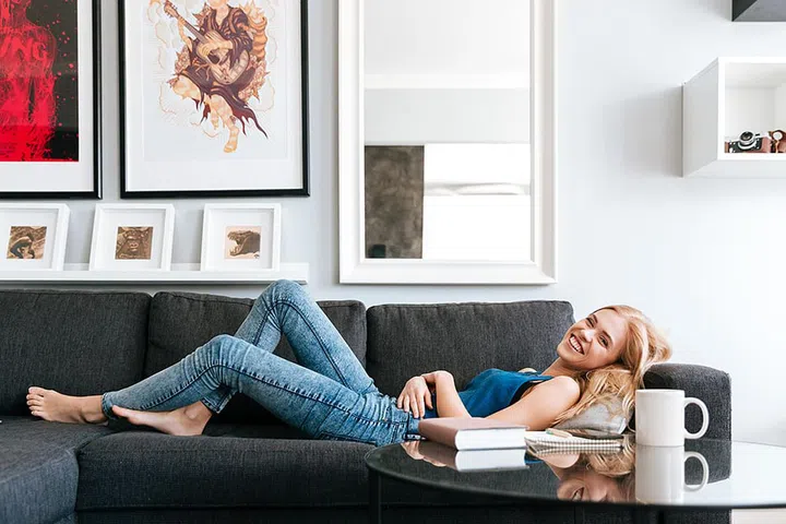 Cheerful attractive young woman lying and relaxing on sofa at home