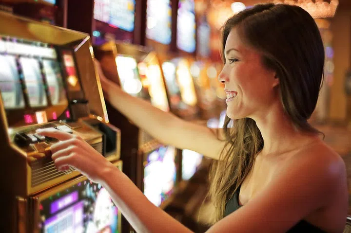 Asian woman gambling in casino playing on slot machines spending money. Gambler addict to spin machine. Asian girl player, nightlife lifestyle. Las Vegas, USA.
