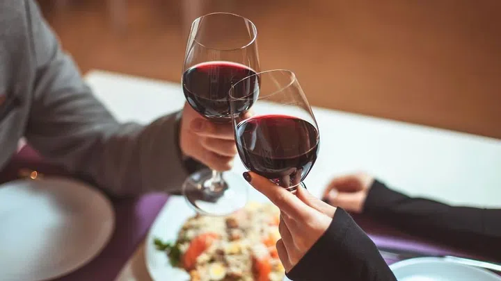 Beautiful young couple with glasses of red wine in luxury restaurant