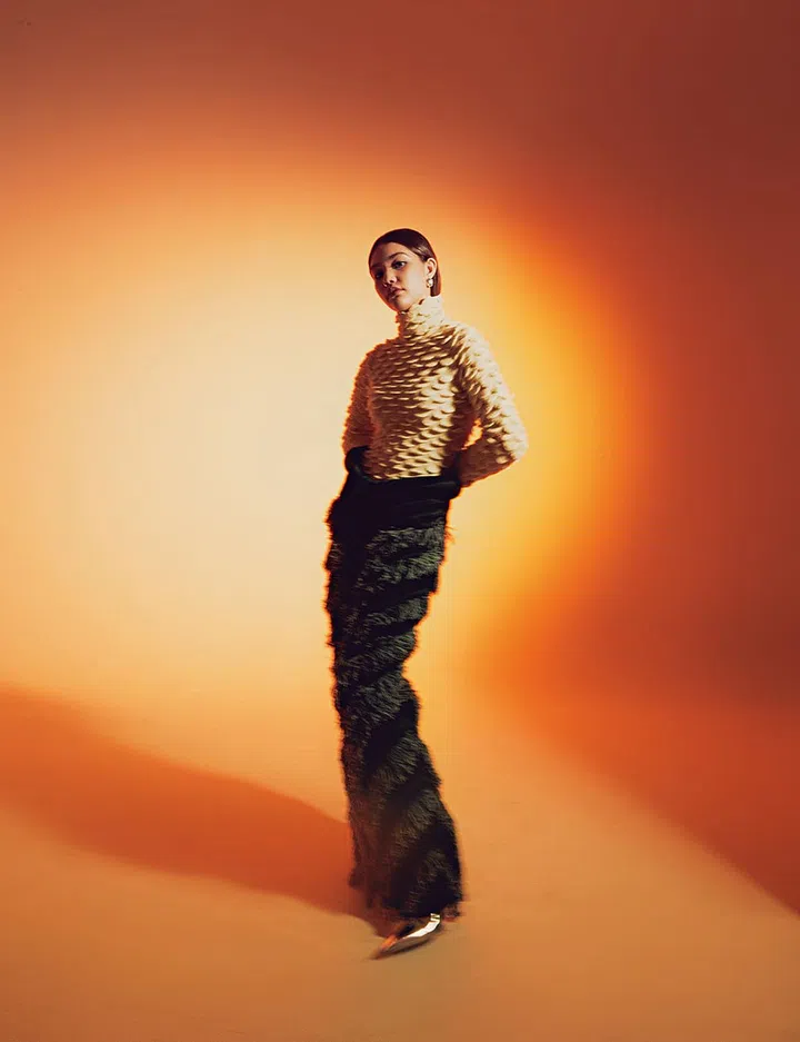 Wool textured turtleneck pullover, wool maxi skirt with feathered panels, metallic knee-high boots, and metallic silver oversized studs, Bottega Veneta