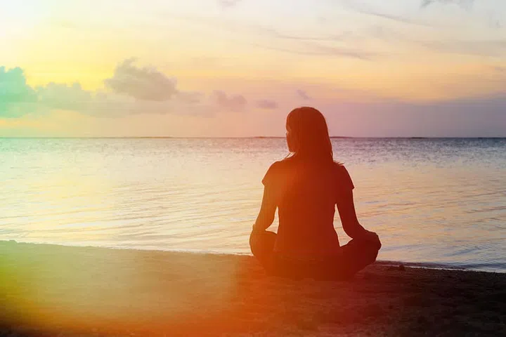 young woman meditation on sunset tropical beach