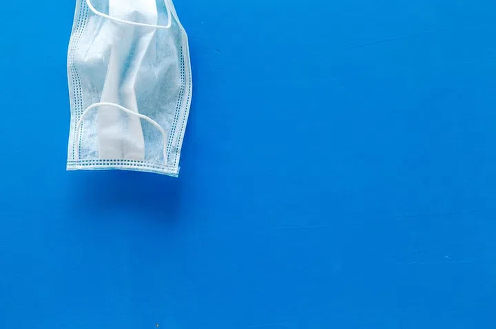 Flu prevention concept. Medical face mask on blue background top view.