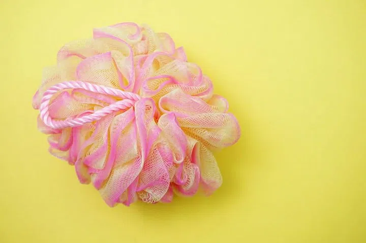 127829065 - pink bath soft with rope on yellow background