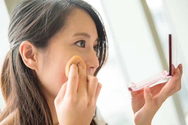 Woman using powder to touch up on her face