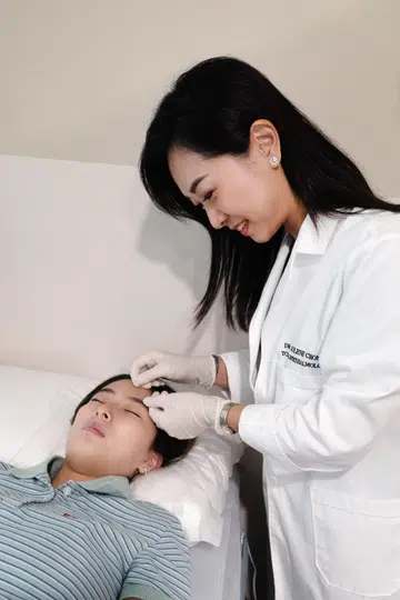 Dr Jolene Chong of Gen Eye TCM clinic administering eye acupuncture on a patient
