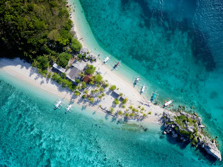 A stunning aerial view of Cabugao Gamay Island in Carles, Iloilo, Philippines, showcasing its iconic white sandbar connecting two lush hills, surrounded by crystal-clear turquoise waters. Part of the Islas de Gigantes archipelago, this uninhabited island’s pristine beauty and dramatic rock formations make it a tropical paradise, perfect for travel, nature, or beach photography projects.